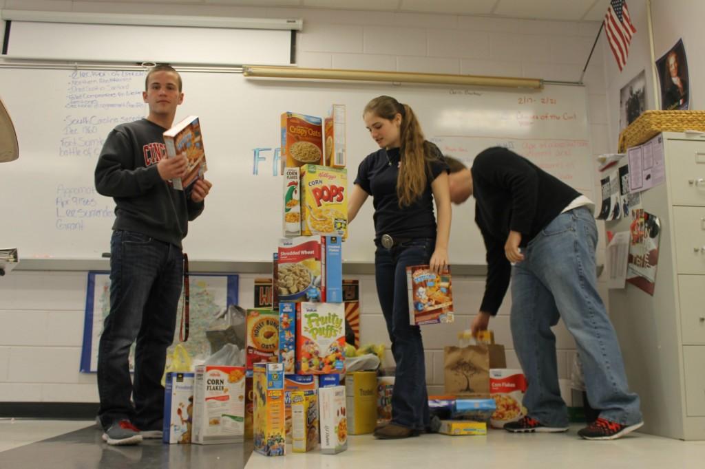 Senior Jordan Sollenberger and juniors Jackie Williams and Landon Holley help stack up the cereal boxes that were collected in partnership with FFA to help feed the homeless at House of Hope.