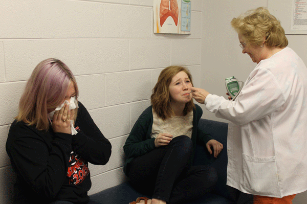 Seniors Payton Loy and Kelsey Edwards completely overtaken by senioritis as nurse Florence White checks their temperatures.