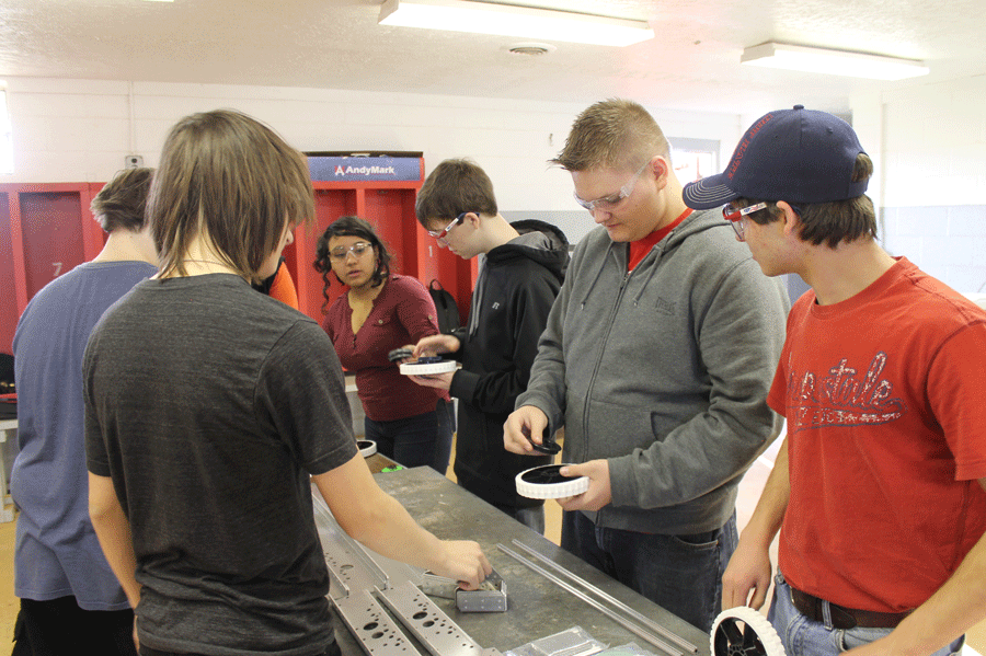 Robotics team members work together on the base of their robot. 