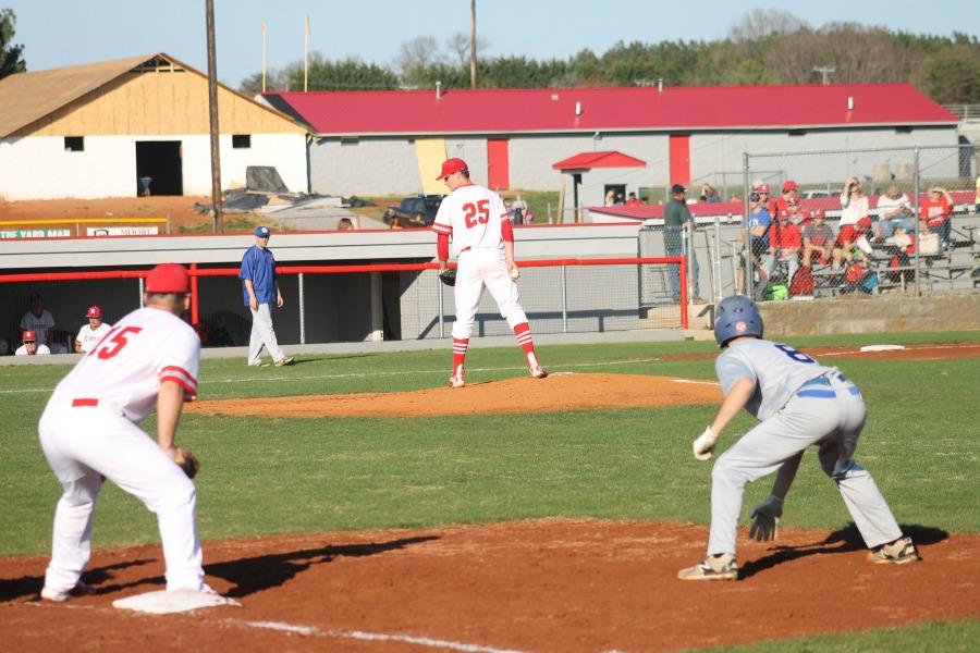 Senior Caleb Thompson waits to pitch while junior Jake Lee makes sure the Dan River base runner is not attempting to steal.