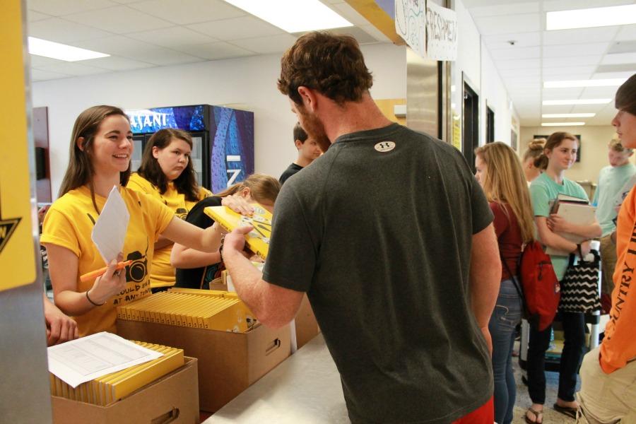 Yearbook editor-in-chief, Logan Patterson, hands out yearbooks. 