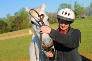 Ms. Brown demonstrates how to put a harness on her horse, Magic.