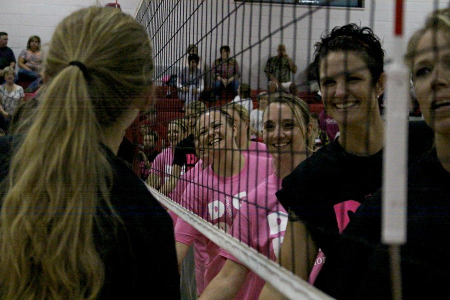 The varsity volleyball team and the alumni wishing each other good luck before the game begins.