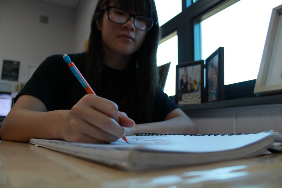 Christine stops for a picture while she is drawing in her notebook.