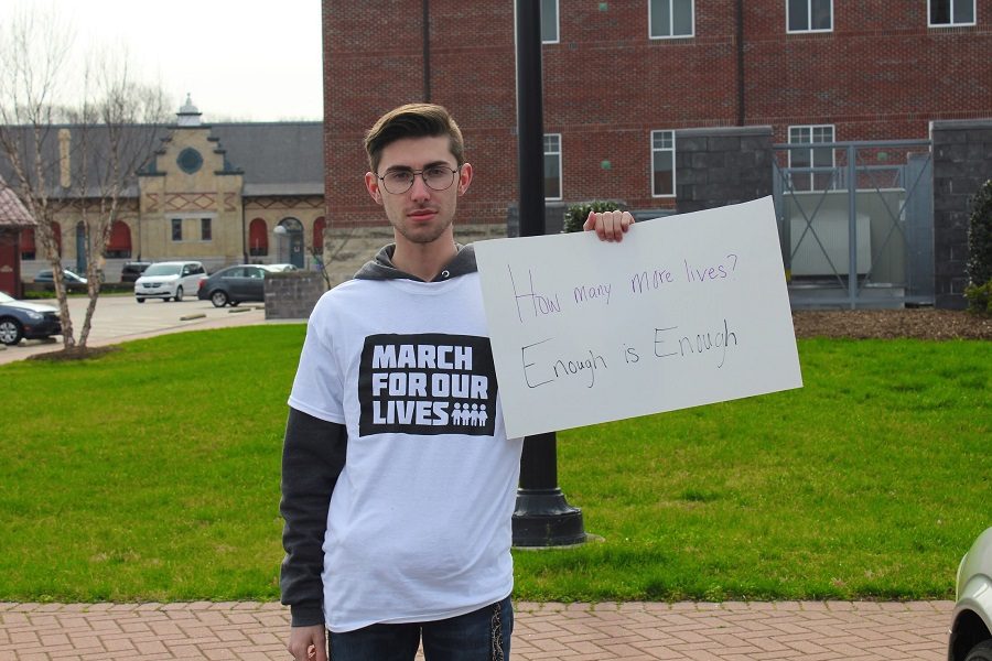 Senior and Organizer, Blake Mitchell, stands with his sign reading, How many more lives? Enough is enough.