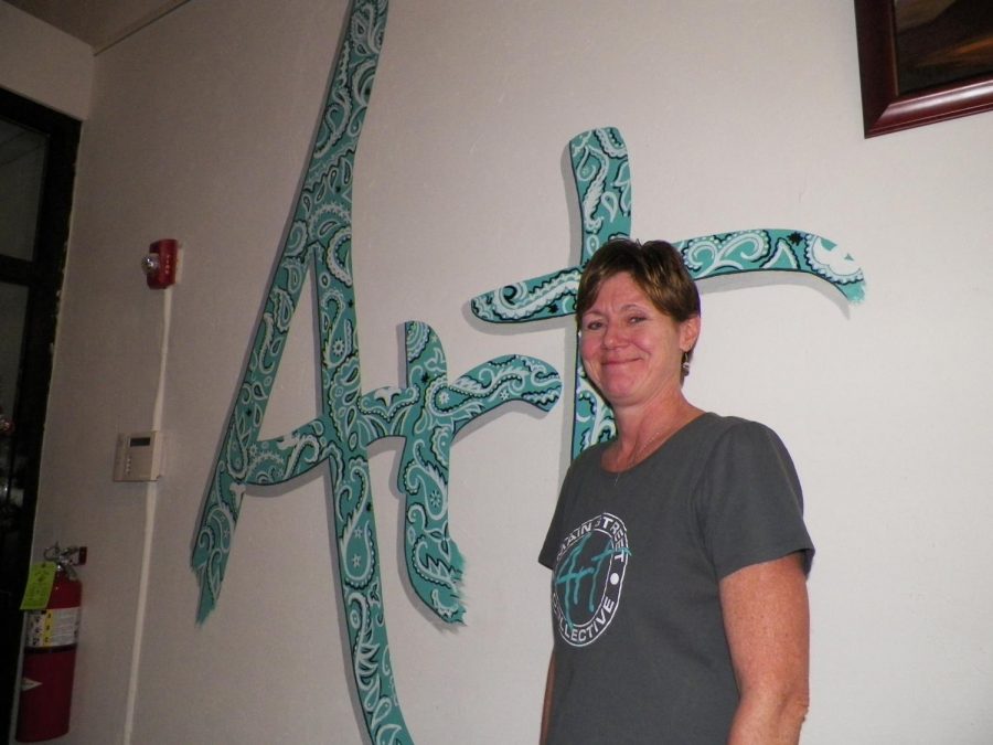 Owner, Cheryl Sutherland, in front of a painted Art. 