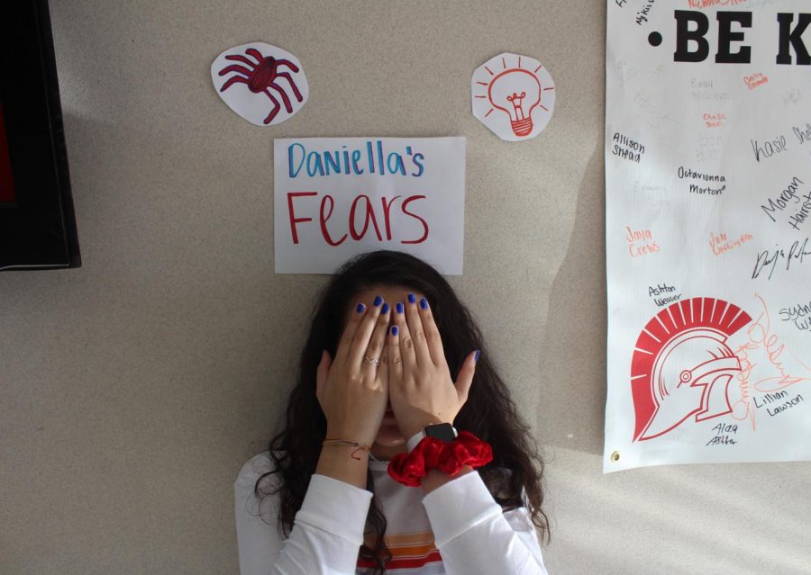 Junior Daniella Espinoza standing under drawings that represent her fears.