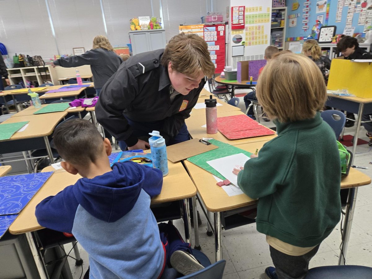 Senior Collin Snead helping first graders sketch their monster. 