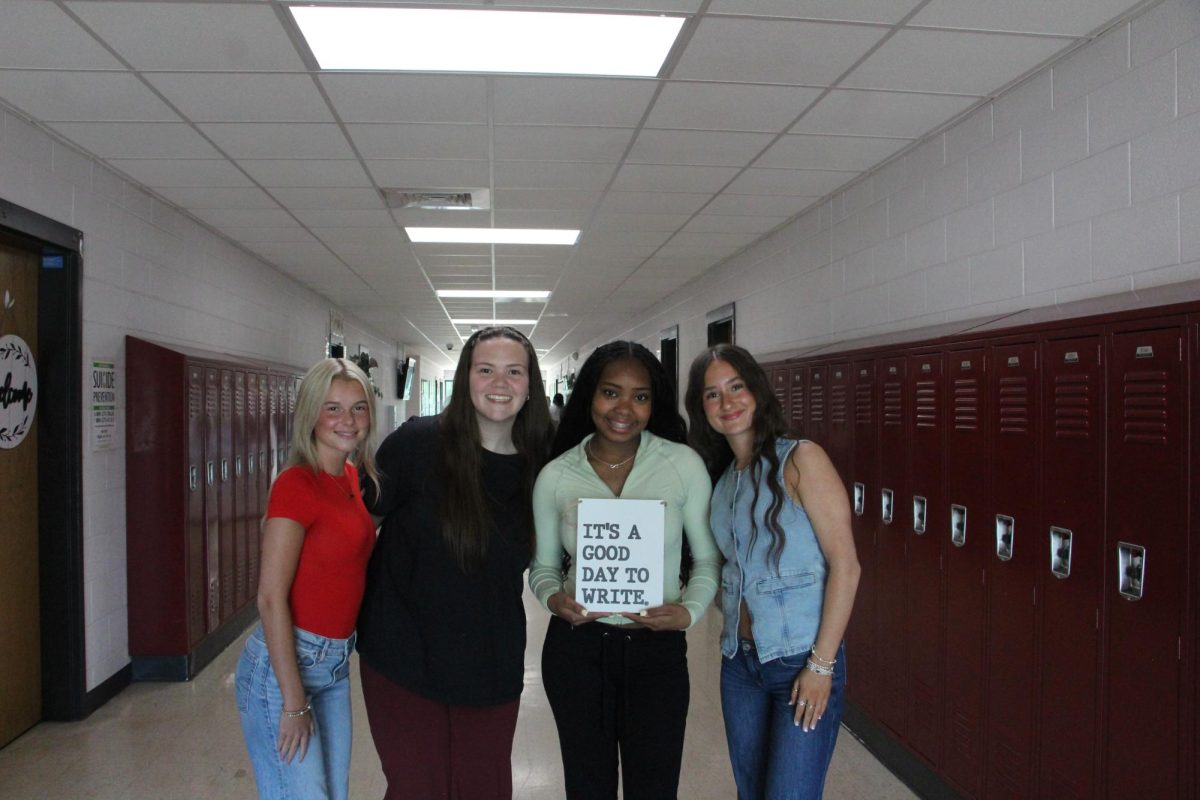 Students posing with Mrs. McGuire's creative writing decorations. 